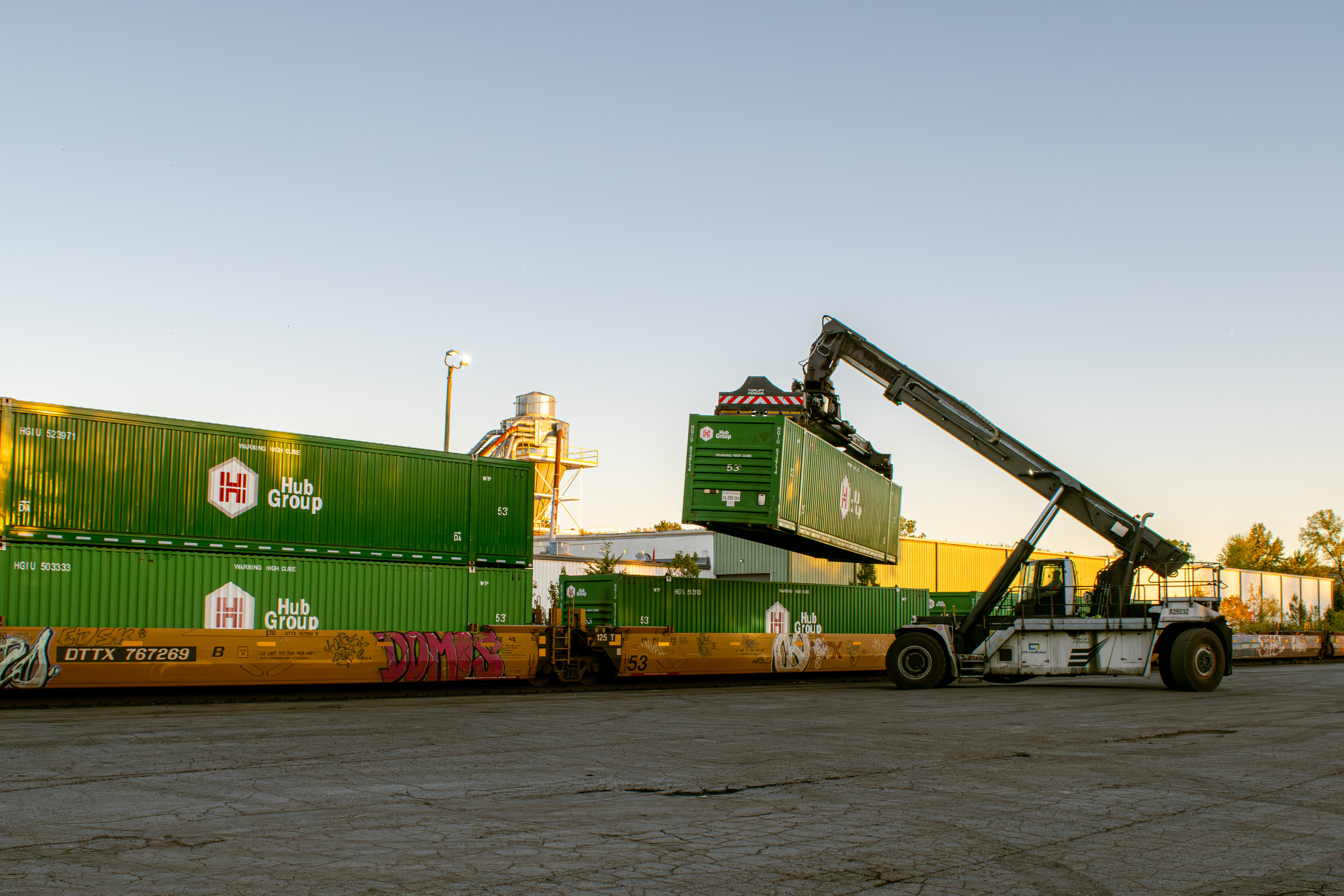 crane truck unloads cargo container from stationary train