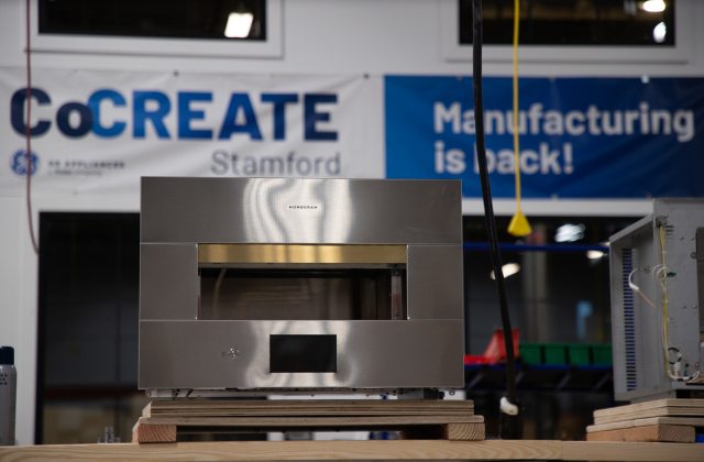 A nice photo of the oven on display in front of a banner that reads CoCREATE Stamford: Manufacturing is back!