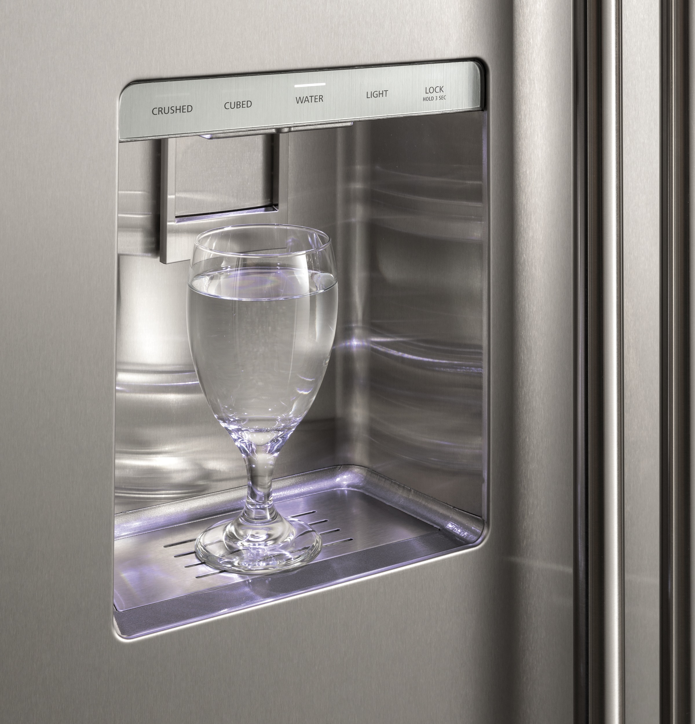 Glass full of water sits in refrigerator door dispenser